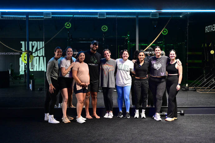 Group of moms and coaches posing together in a gym after a successful class.